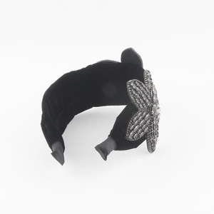 Close-up of black velvet headband with detailed crystal flower and rhinestone accents