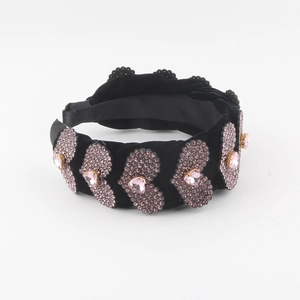 Detailed macro view of pink heart-shaped rhinestones on black velvet padded headband