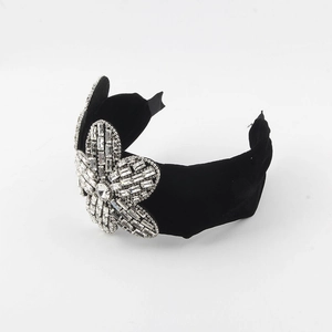 Macro detail of a baroque velvet headband featuring a large intricate rhinestone flower design