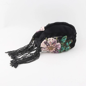 Close-up of velvet headband featuring intricate floral embroidery and long bead tassels