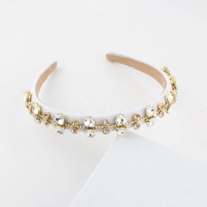 Close-up of sparkling crystals on elegant white fabric headband with golden metal claw settings