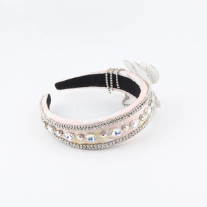 Dettaglio del cerchietto in raso rosa con strass di cristallo e frangia di fiori in tessuto
