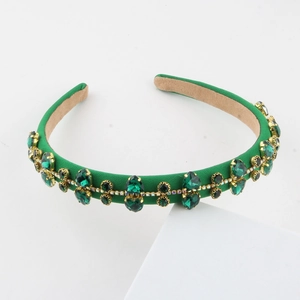 Detailed macro view of luxury green velvet headband with emerald gemstones and golden trim