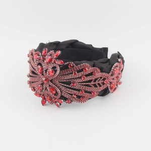 Vue détaillée de la broderie de fleurs en strass rouges sur un large bandeau noir de luxe