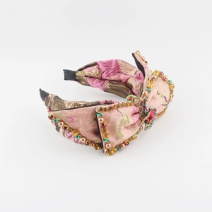 Macro detail of pink jacquard fabric headband with rhinestone and pearl bow embellishments