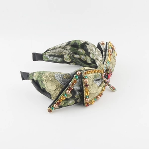 Detailed view of wide vintage headband with floral jacquard and colorful rhinestones