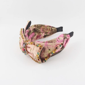 Detail of wide pink knot headband with colorful rhinestones and vintage insect brooch