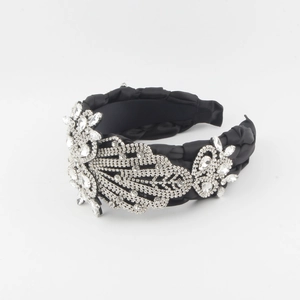 Détail d'un serre-tête en satin noir orné de fleurs argentées luxueuses et de strass