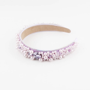 Détail d'un serre-tête en velours rose orné de perles et de fleurs en strass violets