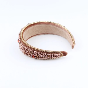 Detail of rose pink velvet headband with pearls, orange rhinestones and gold chain trim