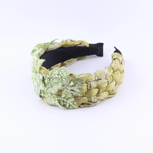 Detail eines grünen bestickten Stirnbands mit Spitzenblumen und Perlen