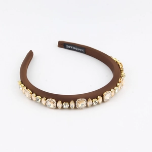 Macro detail of brown satin headband with sparkling champagne crystals and handmade label