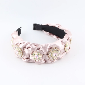 Dettaglio del cerchietto intrecciato in velluto rosa con fiori di strass di lusso