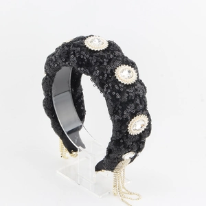 Close-up of black sequined headband featuring oval rhinestones and long tassel chains