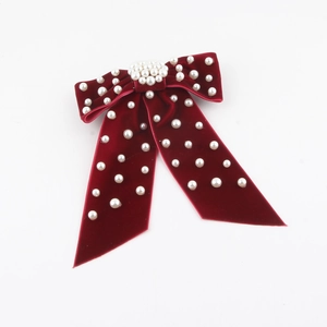Detail of burgundy velvet bow hair clip with embedded white pearls and long ribbons