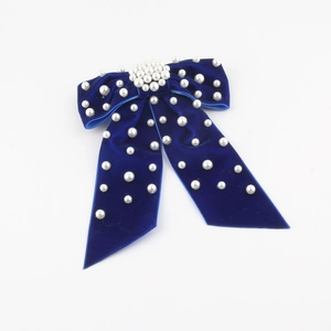 Detail of navy blue velvet bow hair clip with white pearls on a clean background