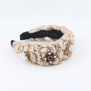 Détail d'un serre-tête tressé large avec paillettes champagne et fleurs en perles de luxe