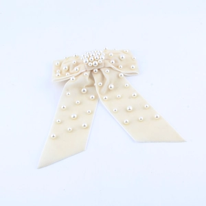 Detail of cream velvet bow hair clip with embedded white faux pearls for elegant styling
