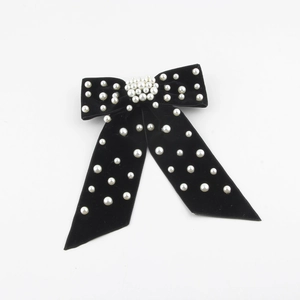 Detailed view of luxury black velvet bow hair clip with elegant white pearl embellishments