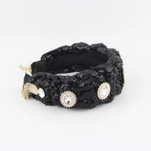Detail of twisted black sequin headband with oval crystals in gold settings