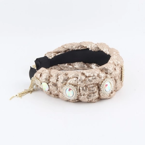 Detail of champagne gold knotted headband with colorful rhinestones and gold fringe accents