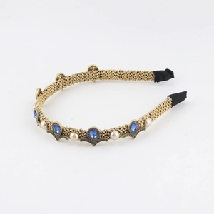 Baroque style gold braided headband with blue gemstones and white pearls on white background