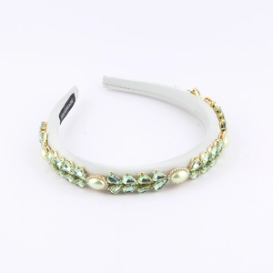 Detail of handmade light green crystal and faux pearl embellishments on a satin headband