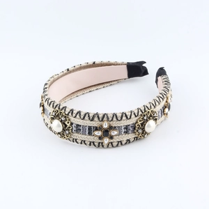 Detail of knitted headband with gold floral filigree, white pearls and sparkling rhinestones