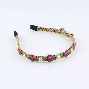 Detail of vintage gold braided headband with rose red gemstones and faux pearls