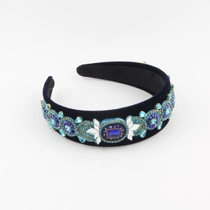 Close-up of navy velvet headband with luxurious blue rhinestones and gold bead accents