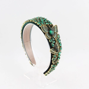 Macro shot of green velvet headband with baroque emerald crystals and gold butterflies