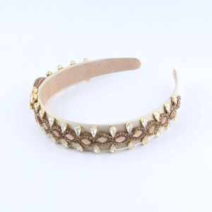 Detailed view of beige baroque headband with crystals and rhinestones on white background