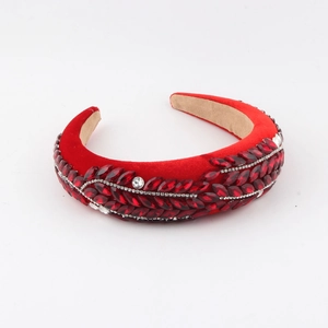 Detail view of red velvet headband with intricate leaf patterns of red and white rhinestones