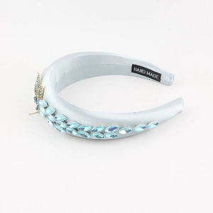 Détail d'un serre-tête en satin bleu clair avec pierres bleues et détail papillon doré