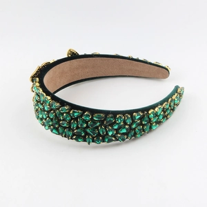 Close-up of luxury dark green velvet headband with intricate emerald crystal embellishments