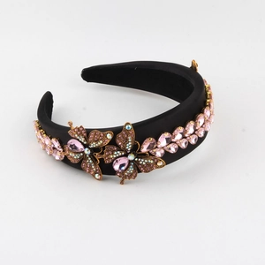 Detailed view of black satin headband with pink crystals and golden butterfly ornaments