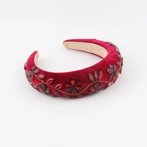 Detailed view of burgundy velvet headband with rhinestone flower and gold chain trim