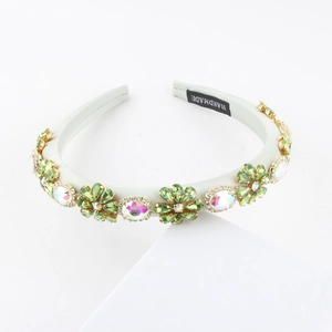 Close-up of handmade baroque headband featuring green floral rhinestones and gold claws