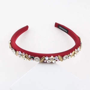 Serre-tête rembourré rouge foncé avec strass, perles et détails dorés sur un bloc blanc