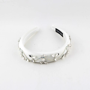 Close-up of white satin headband with crystal flower pattern and hand made label details