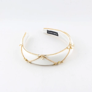 Detail eines weißen Satin-Haarreifs mit goldener Kette, Kristallen und Handarbeitslabel