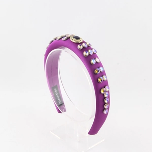 Détail d'un serre-tête en satin violet avec cristaux arc-en-ciel et pierre noire