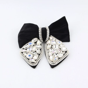 Macro detail of black velvet hair claw clip with shimmering rhinestones in bow design