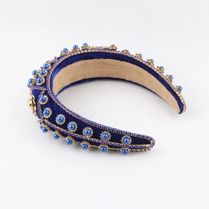 Detailed shot of royal blue velvet headband with blue pearls and gold lion head emblem