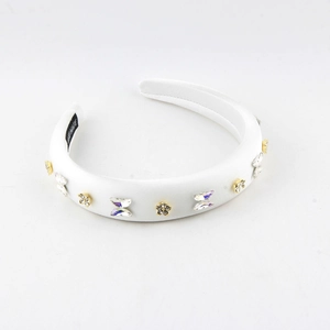 Detailed view of white satin headband with butterfly rhinestones and gold flowers