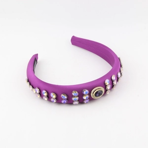 Détail du serre-tête large en satin violet avec strass et pierre précieuse centrale