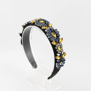 Detailed view of floral crystal headband with blue and amber stones on acrylic stand