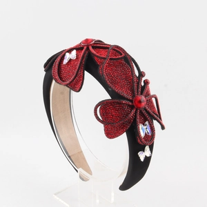 Detailed macro of red rhinestone floral and butterfly elements on a wide black headband