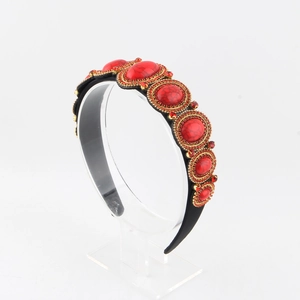 Detail of red rhinestone headband with vintage gold metal accents and black wide base