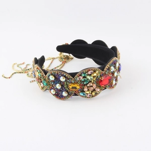 Détail d'un serre-tête baroque large orné de strass colorés et de chaînes dorées